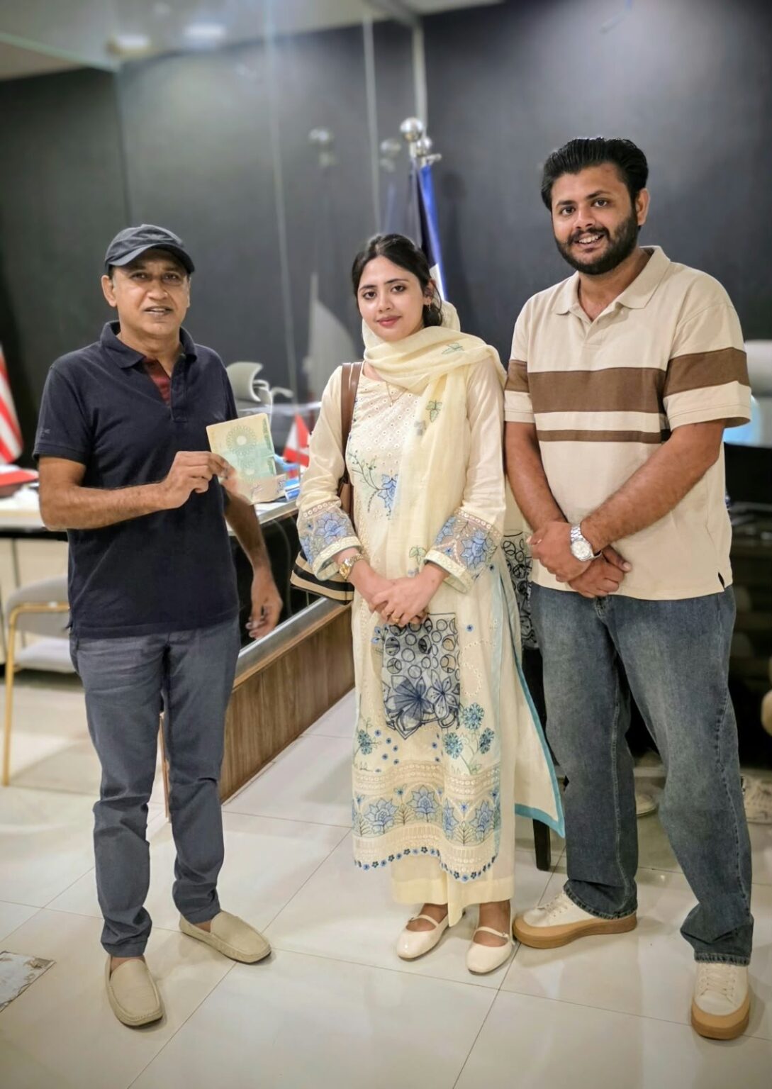 Mujtaba Maharvi with a young couple holding their approved visa at the Westside office
