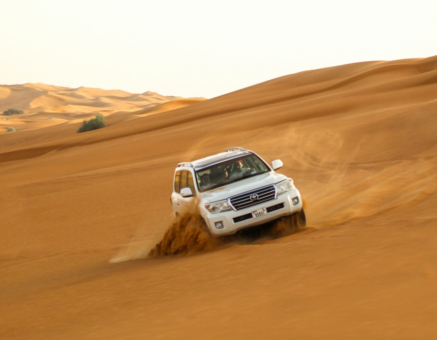 A four by four driving over golden dunes on a desert safari