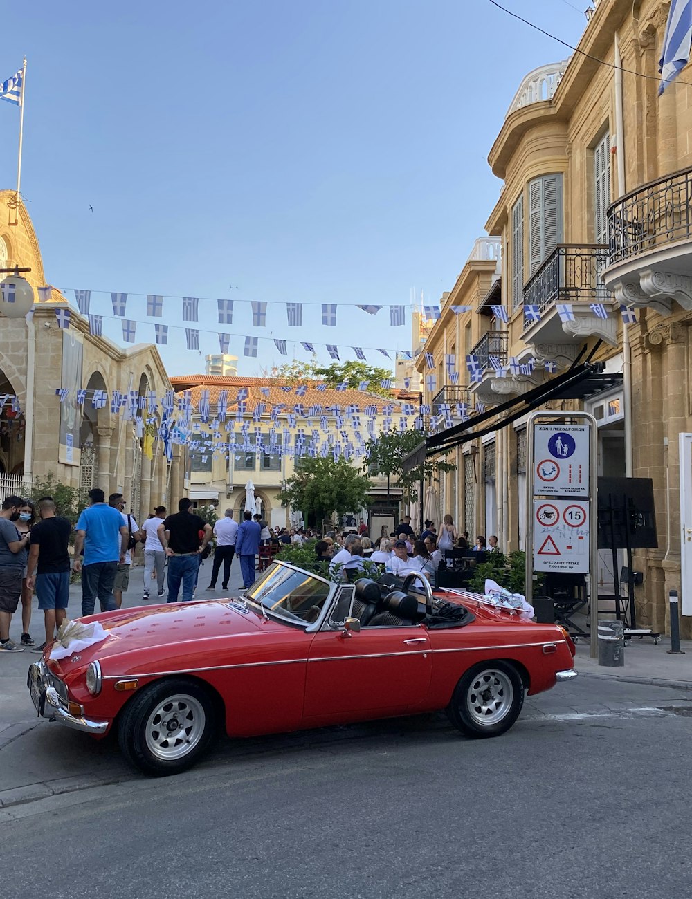A sunny old town street in Nicosia with a classic red car and cafés