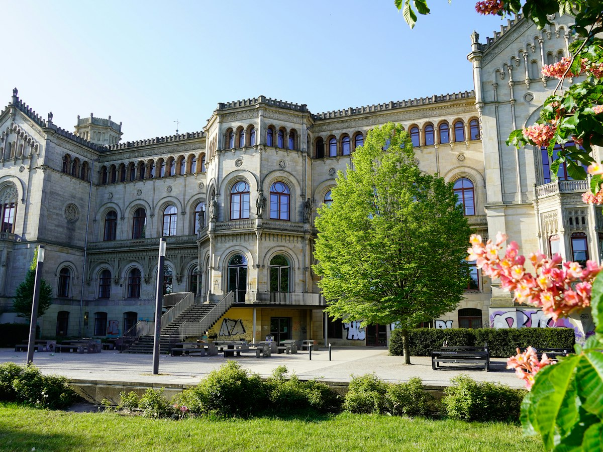 A historic European university building with spring blossom
