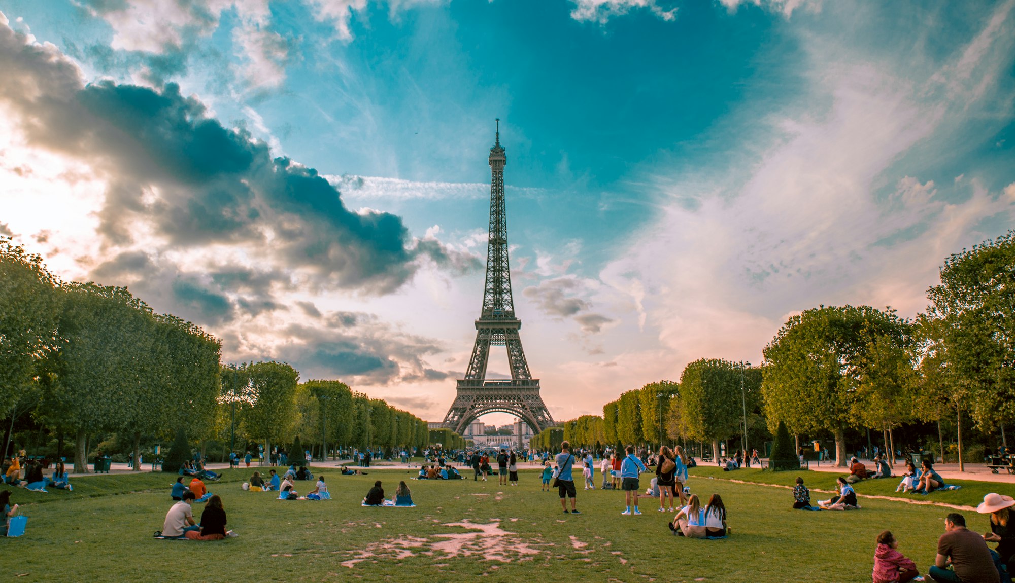 People relaxing on the Champ de Mars lawns below the Eiffel Tower on a sunny day