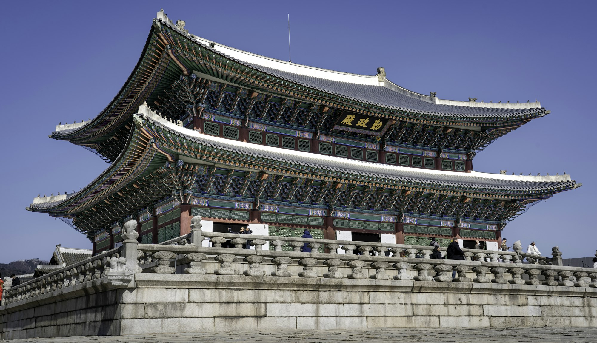 The painted eaves of Gyeongbokgung Palace in Seoul under a blue sky