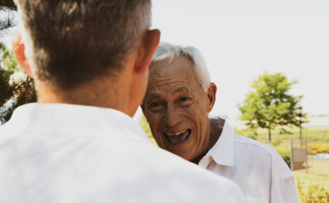 An elderly father smiling with his son