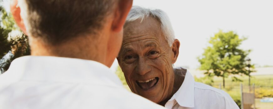 An elderly father smiling with his son