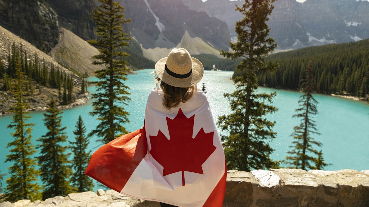 A traveller with a Canadian flag by a mountain lake