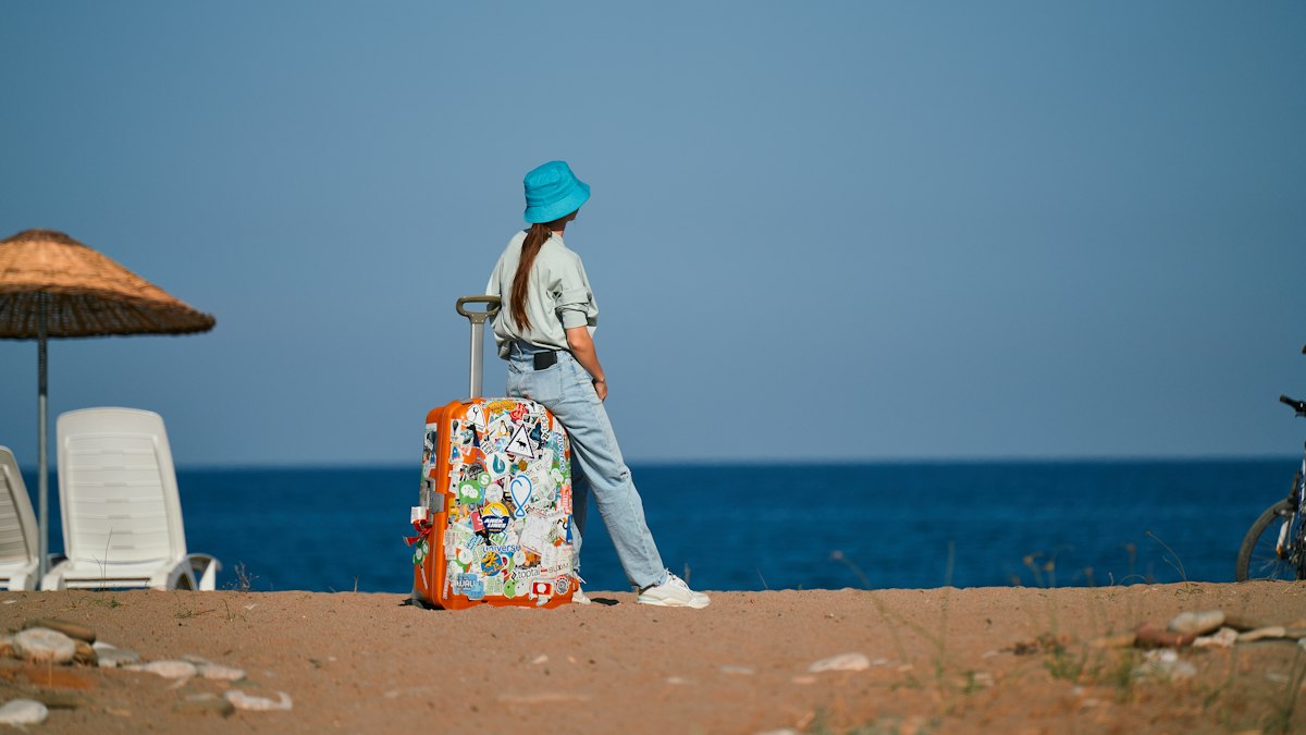 A young traveller with a suitcase by the sea