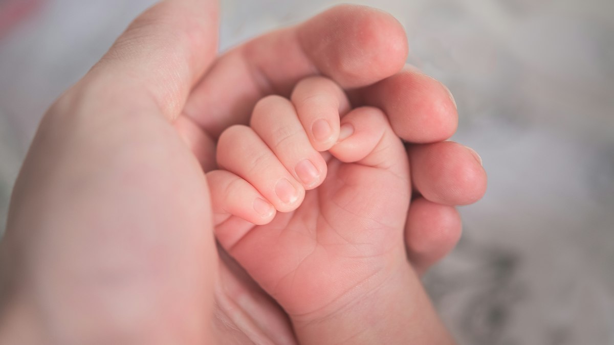 A baby holding a parent's finger