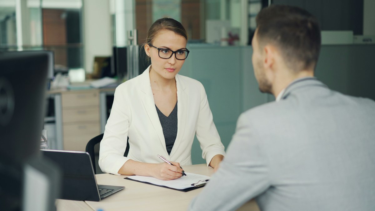 Two people talking across a desk in an office