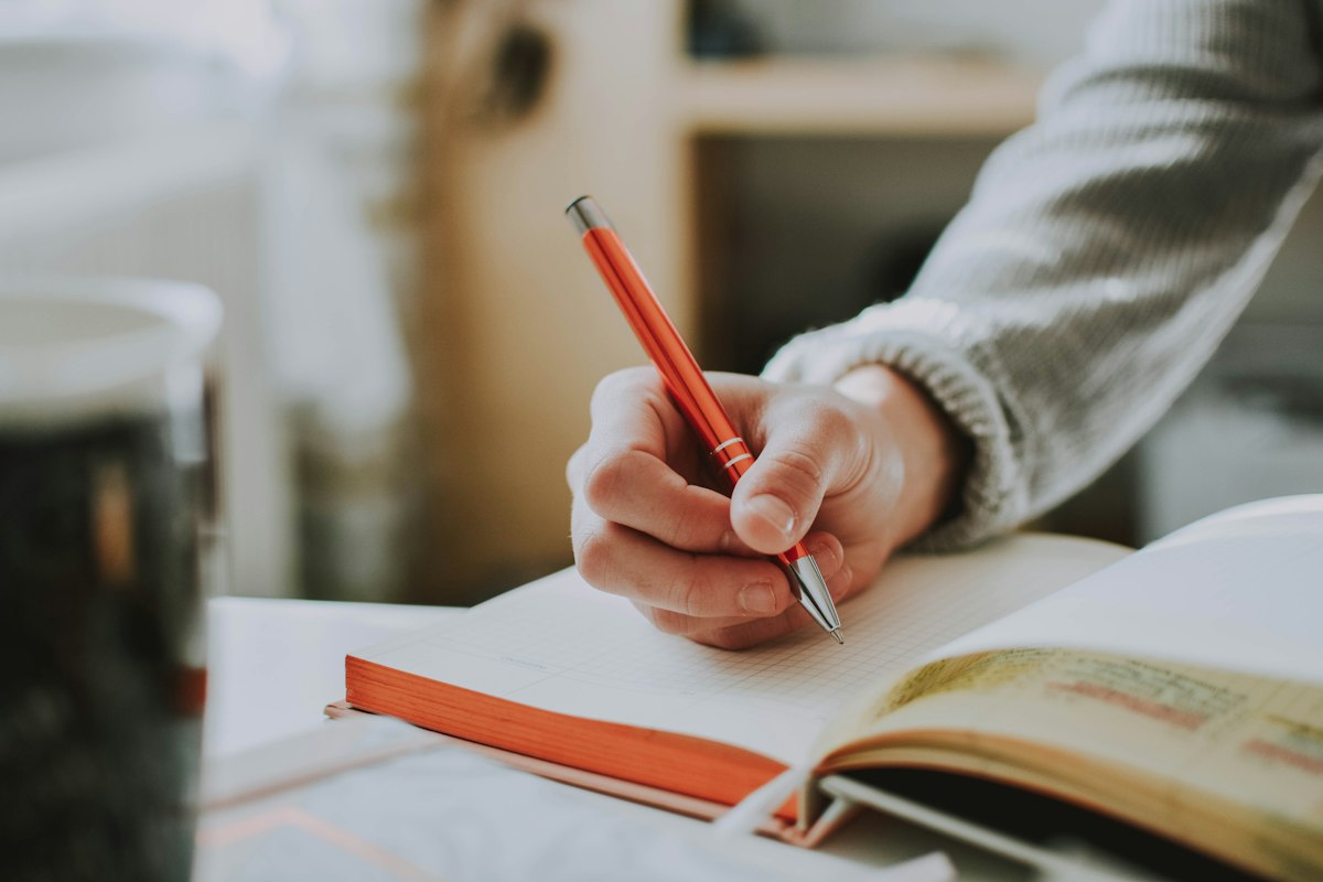A student writing notes with a red pen