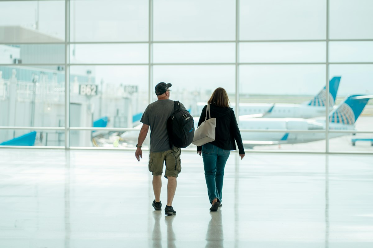 A couple walking through an airport terminal with luggage