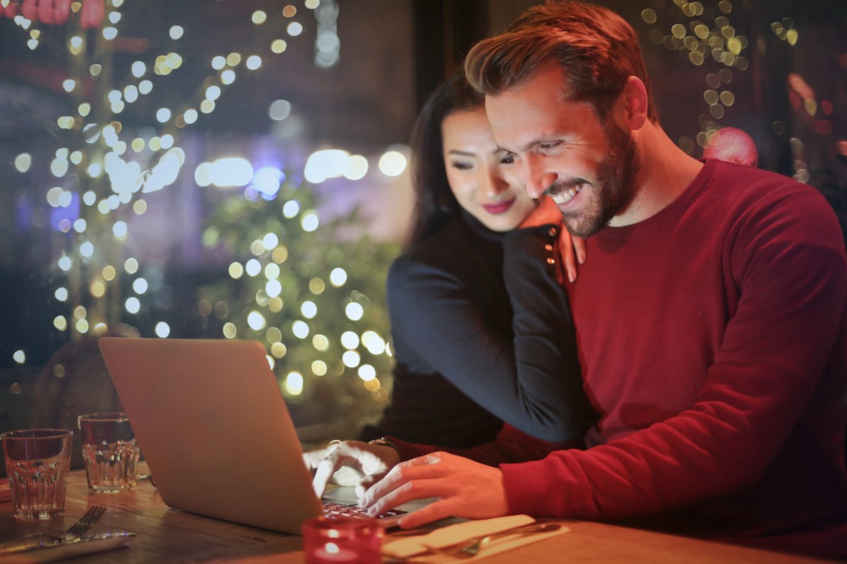 A couple smiling while planning on a laptop at home