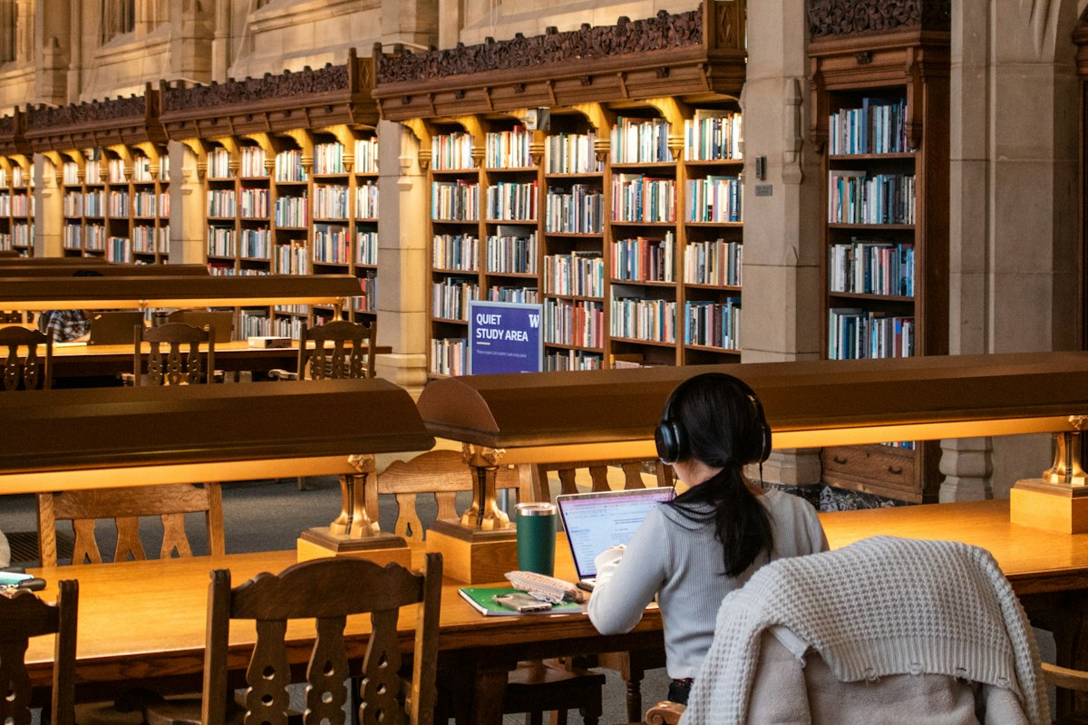 A student studying in a large historic university library