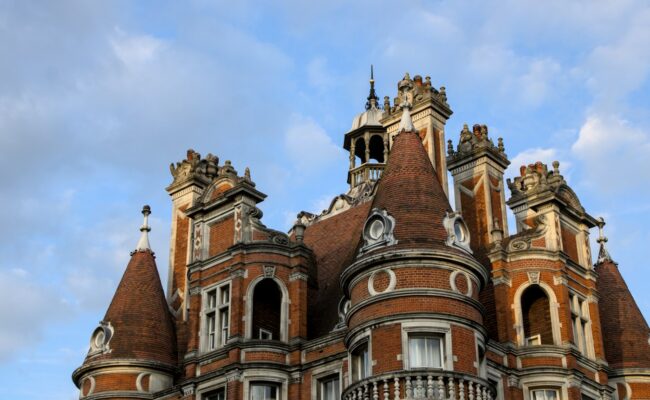 A grand red brick Victorian university building under a blue sky