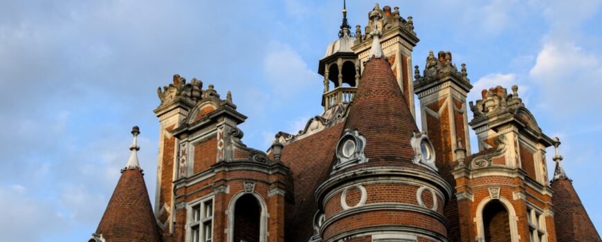 A grand red brick Victorian university building under a blue sky