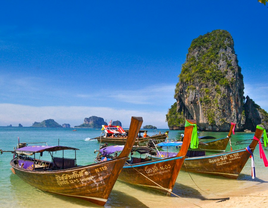 Longtail boats beside limestone cliffs in Krabi