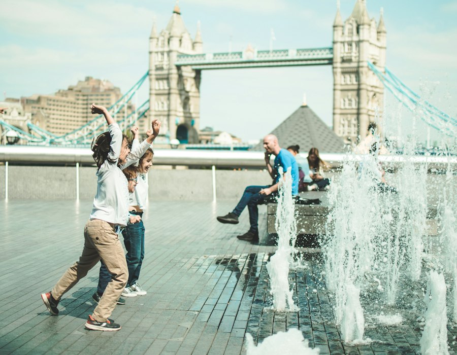 Friends playing by the fountains near Tower Bridge in London