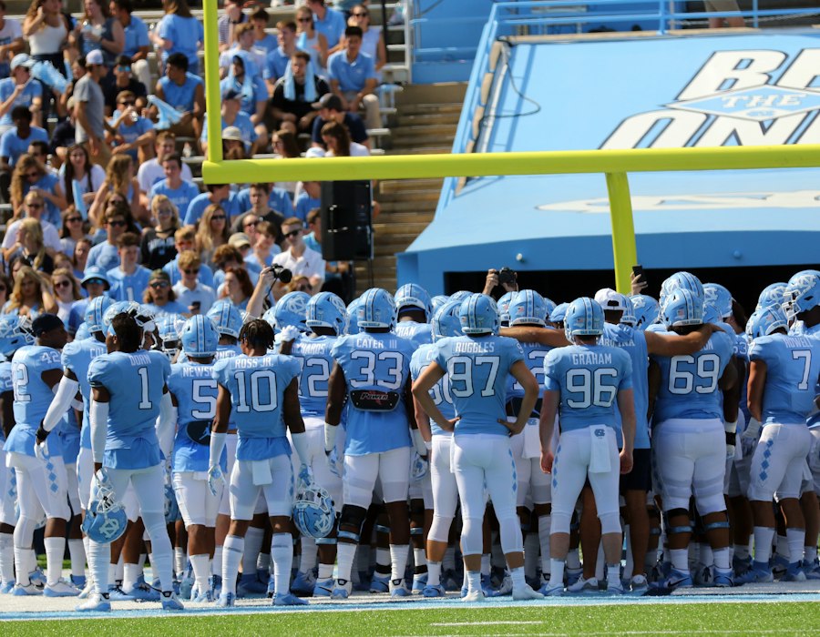 A college football team running onto the field in a packed stadium
