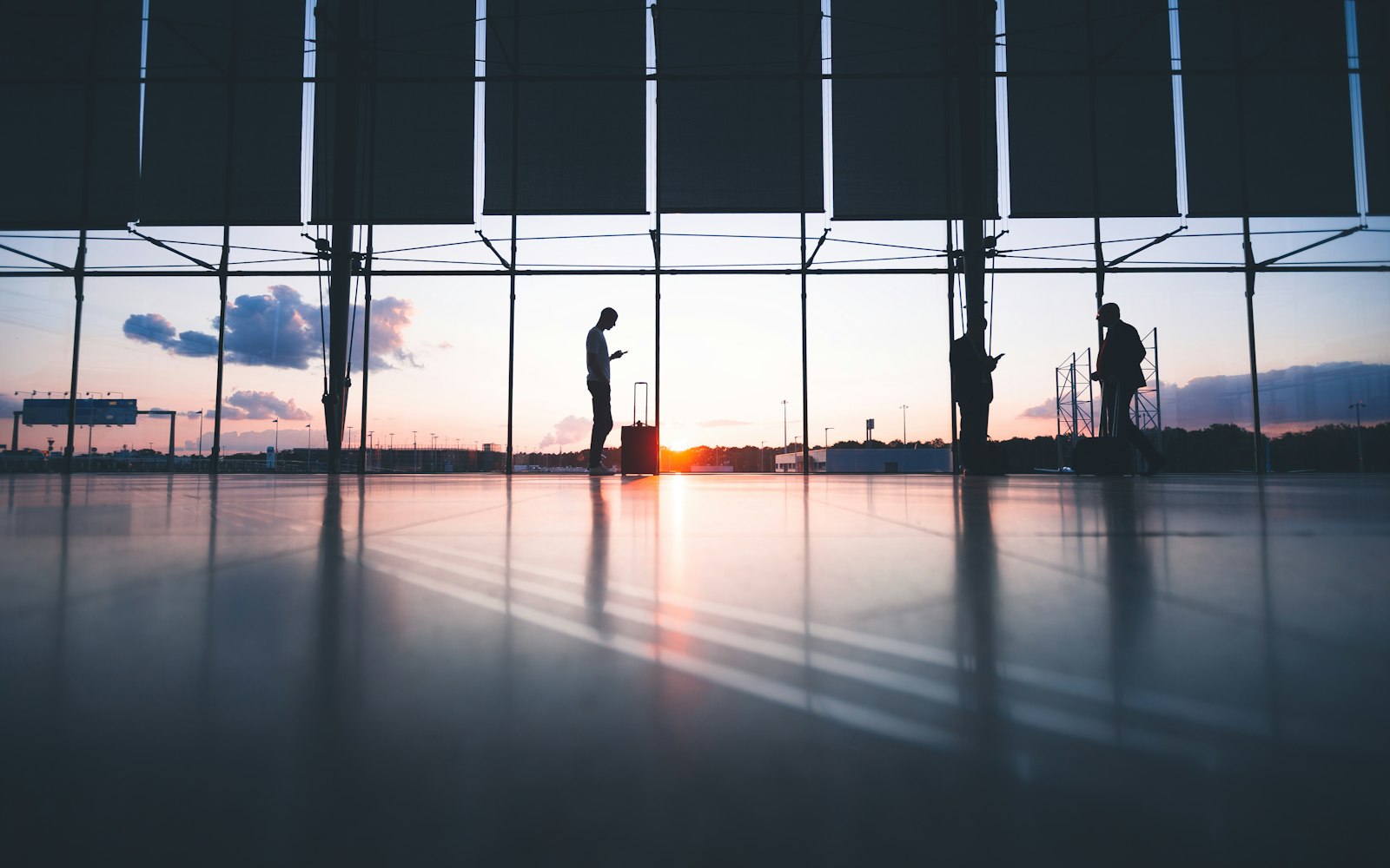 Travellers at an airport window as a plane taxis outside