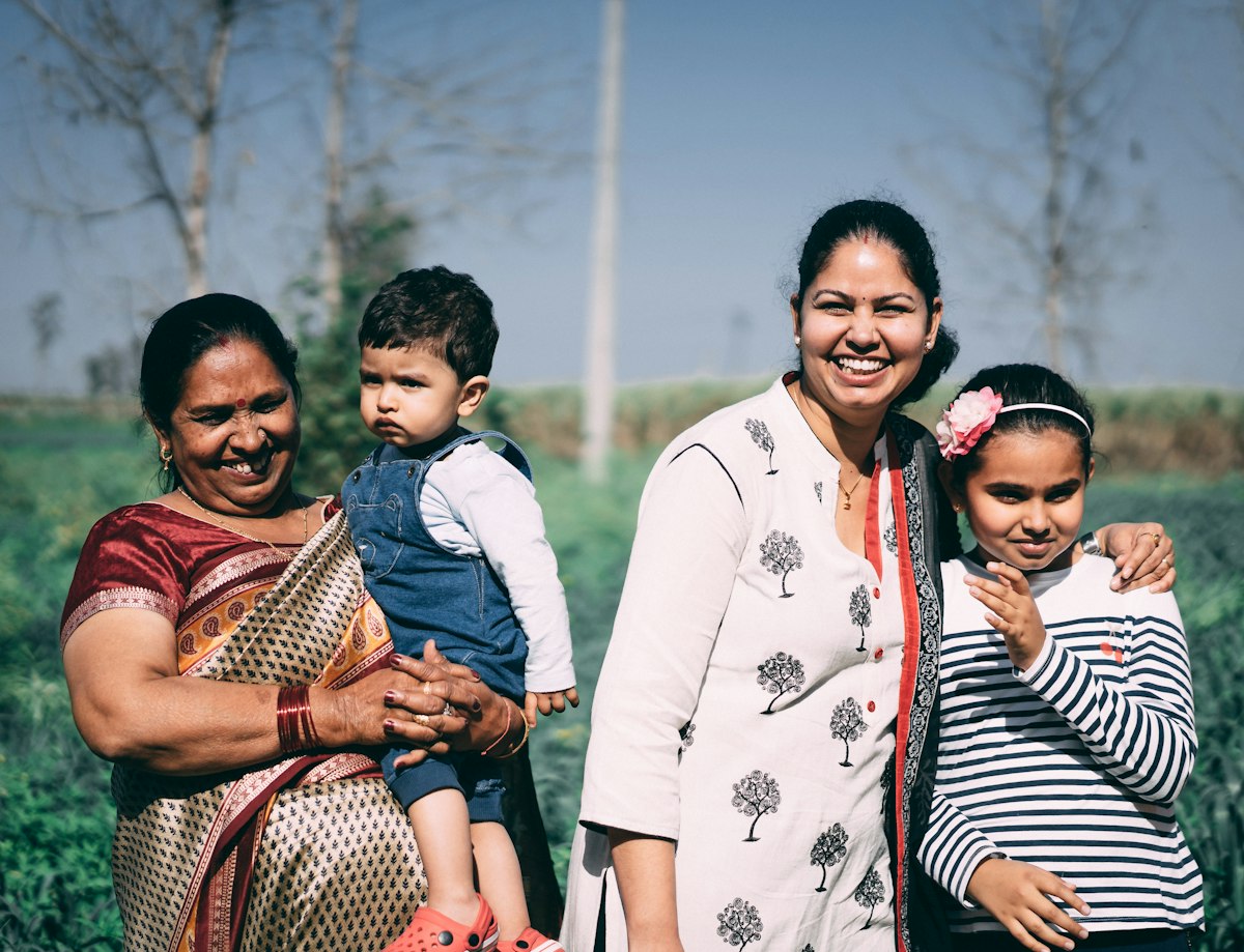 A Pakistani family of three generations smiling together, the people behind a sponsored visit application