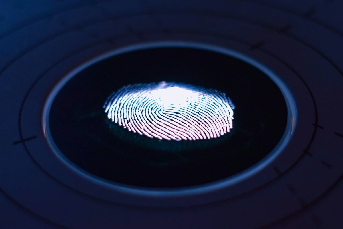 A glowing fingerprint on a scanner; UKVI matches enrolled fingerprints against all Home Office holdings