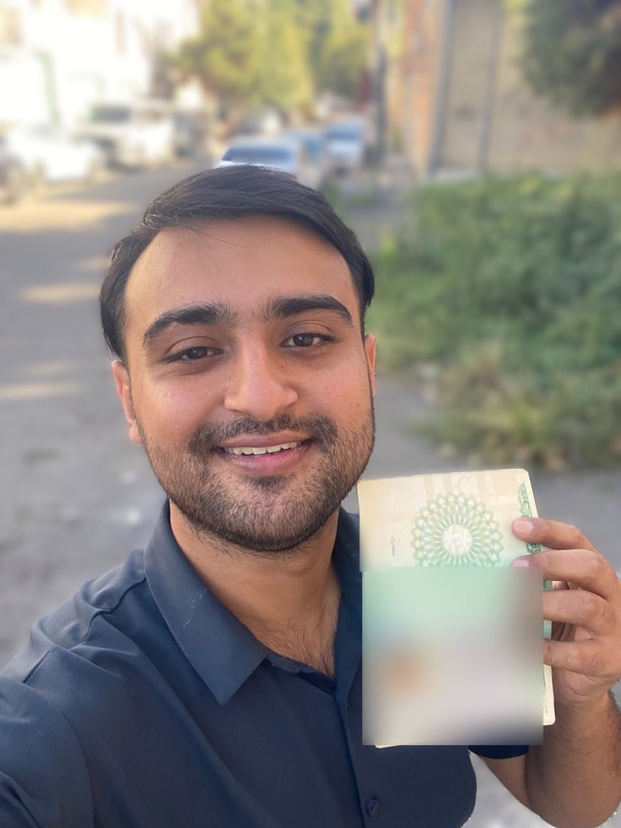 Saad smiling and holding his passport with his new French student visa, on his way to KEDGE Business School