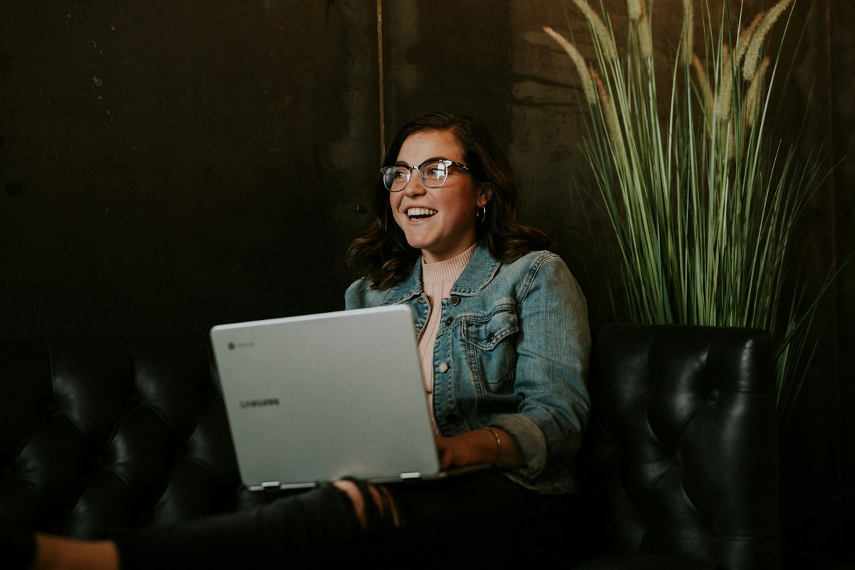 A smiling young woman at home with a laptop, ready for an online UKVI credibility interview